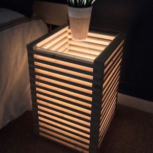 Horizontal wood slats connected and lit up bedside table.